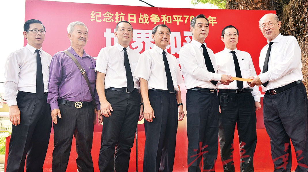 中国驻槟总领事吴骏移交1万5000令吉捐款予公民学校纪念碑管委会主席督庄耿康接领。