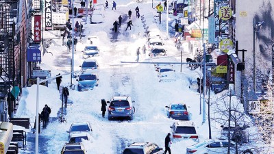 以美国纽约唐人街,群众清除覆盖汽车的积雪。