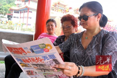 信徒抢先阅读《光日报》报道妈祖海巡活动。