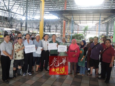 峇央峇鲁巴刹公会及美食中心小贩公会代表手持纸卡反对槟岛市政厅张贴通告,禁止8项行为,左6为国阵班台惹查协调员郑两明、左七峇央峇鲁巴刹公会主席陈健强、左一民政党槟州峇央峇鲁区部青年团团长许翔铭及左三班台惹查小贩中心协调员邱炎和。