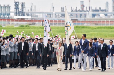 小池百合子(中)手持奥林匹亚会旗步下飞机。