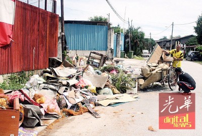 居民以三轮车载已损坏的地毯等丢在路边,等候垃圾车前来收拾。