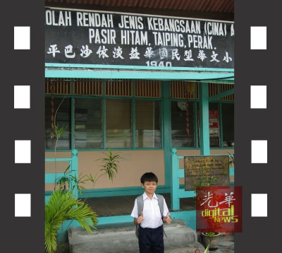 萧顺洋站在益华小学前拍照。