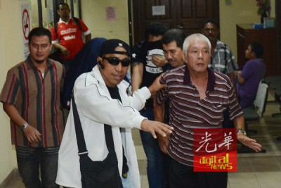 右一身穿横线条T恤的大年男子企图拍打本报摄记,以另帮忙开路的朋友立即安抚,避免节外生枝。