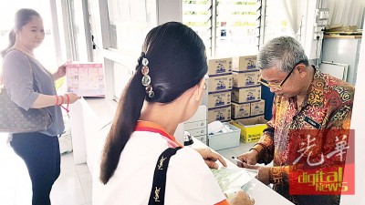 家长前往槟华小学,提交网上新生报名文件予该校老师。
