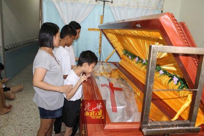 死者家属看着死者遗体感伤心。