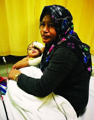诺莫哈末已包了纱布，并躺在母亲怀里，等候住院观察。