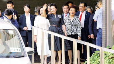 彭丽媛去时向现场传媒挥手。