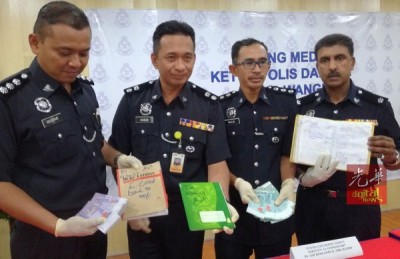 哈比比(左2)与立功警官在记者会出示贩卖人口组织所使用的买卖记录簿,右是金马警区刑事调查主任古纳南副警监。