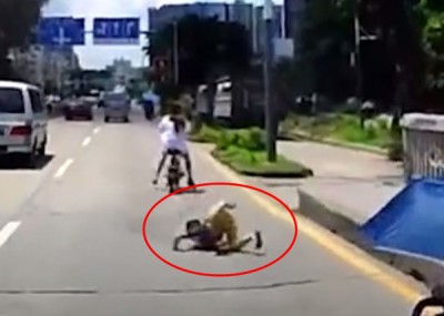 男童(红圈)以路面颠簸,起摩托车后座跌落地面。