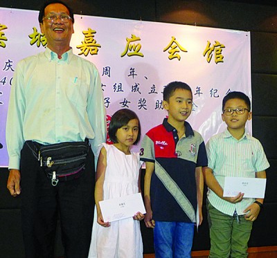 嘉应会馆干事周新才颁奖学金予受惠学生。