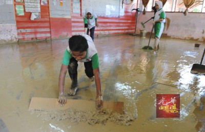 达瑙国小学生在水灾后,纷纷回校清理被泥水蹂躏的校园与课室。