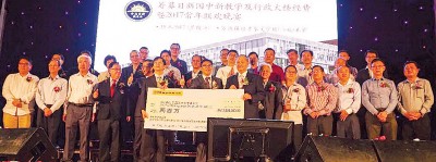 陈治中(左6)在众校友见证下,移交200万令吉模拟支票予郑奕南(右7),中为谢克胜。
