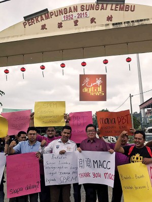 再迪(左2起)、范清渊与支持者在双溪里武村前高举大字报,感谢反贪会取缔行动。