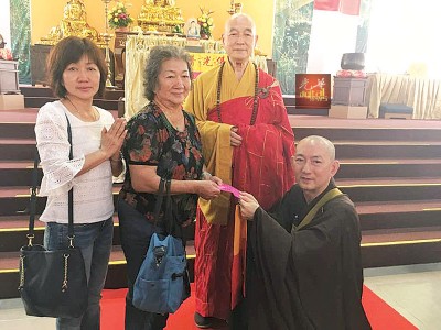  刘子贤在慧海法师见证下把“落发”送给妈妈纪念。左为刘秀华。