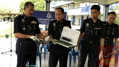 诺依里斯(左)跟一多警官示出派出所所起获到的手提电脑等物品。