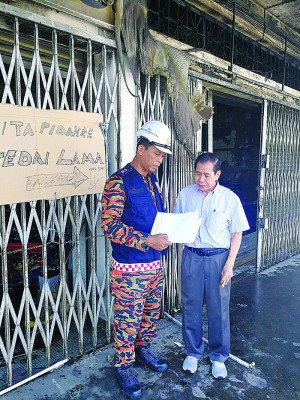 被大火光顾的店面前悬挂着告示,通知顾客该公司暂时迁移至旧址营业。