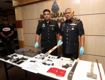 莫哈末扎尼(右)与立功警官出示匪徒的作案工具、失车车匙与一些遇劫财物。