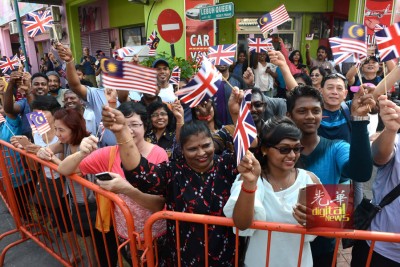 民众手持我国及英国国旗,头顶艳阳,夹道欢迎王储伉俪抵达。