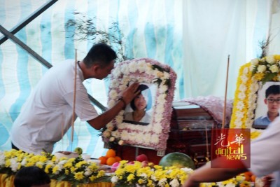 林瑞木不舍地觸摸兒女遺照,並打開女兒喜愛的餅乾放在靈前。