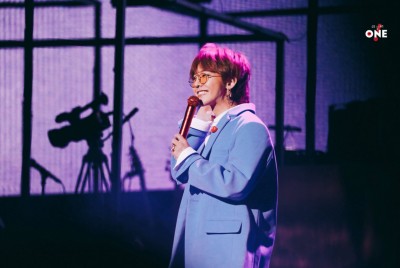 GD以顺毛浏海配蓝色大衣、橘红色太阳眼镜现身IU的演唱会。