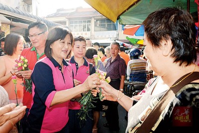 吴秀丽(左)趁着308国际妇女节为妇女们献上一朵花。