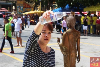 现场除了参与者互相泼水之外,一名妇女也手持白开水往佛像淋上,祈福事业顺利 。