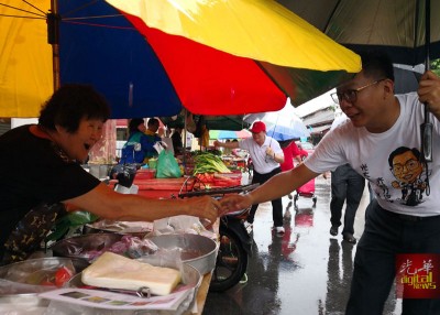 大雨不阻扰!郑来兴及曹观友手持雨伞继续拜票。