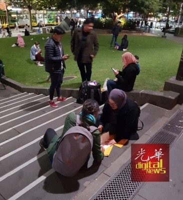 身在澳洲的海外选民席地而坐填写邮寄选票,准备托回国的大马人送到选举官手上,履行身为大马公民的义务。(图取自Joshua Ong家和脸书)