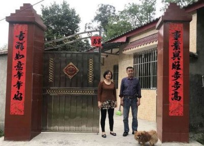 李克诚和妻子在震后重建的房屋前合照。