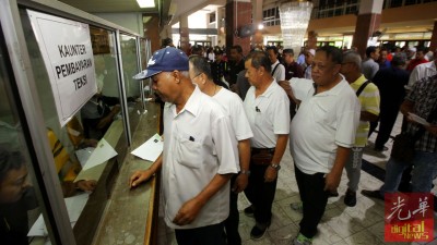 的士司机在槟州大会堂柜台处排队领取奖励金。