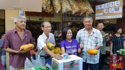 (右2起)王丽丽、罗盛泉响应义卖,捐款“救国”。左为洪顺进,右为甘榜峇汝社委会主席陈汉荣。