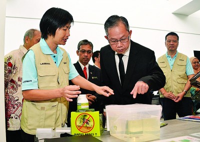 李文材(右)浏览展出摊位,刺探孑孓杀虫剂功能。