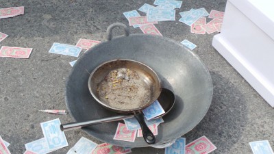 炒锅里的一盘沙石,讽刺商企业者罔顾村民生计,如同在他们饭碗里倒沙。