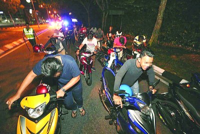 遭到检举的摩托骑士被警方训令各自推著摩托车步行2公里到交警执法组总部。
