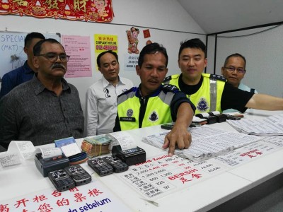 罗海米(左2)展示非法赌博中心里之器材、票根和生淌指南。