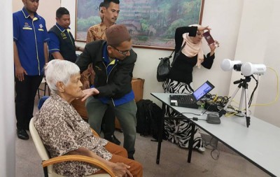国民登记局流动登记队职员细心为老人梳理头发、调整角度,拍下新身份证照。