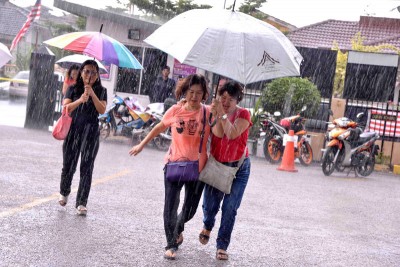 无拉港下起了滂沱大雨,选民们撑伞快步行走。