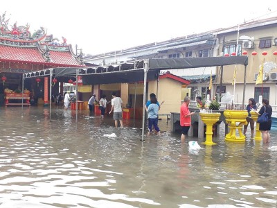 信徒在雨后涉水而过。(照片取自巴生直落玻璃凤山寺脸书专頁)