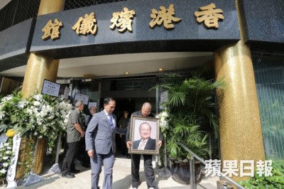 查良镛之男查传倜拿父亲遗照步出殡仪馆。