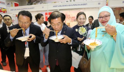 陈国伟(中)为“一带一路”陕西特色商品展览会开幕后,品尝参展的美食。