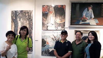 画家韩彪在他的作品前与好友合照。