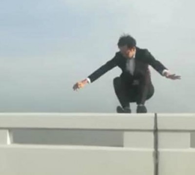 男子爬上桥堤,面对镜头直播。