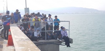立在大桥路肩的记者们长时间顶着太阳曝晒守住现场。