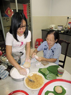 黄瑞金（右）把制作鼠壳粿的本领功夫传授给孙女林奕思。