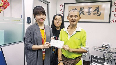 本报人力资源部暨行政部高级经理周慧妮（左）周四移交5000令吉支票予彭德光（右），顺祝其身体安康。