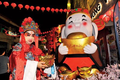 当“猪财神爷”打扮的民众遇上《光华日报》设立的“卡通大财神猪”。