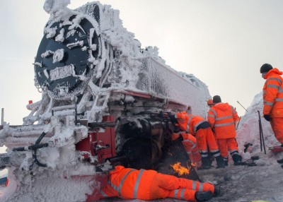 德国救援人员协助被困大雪中的火车前进。