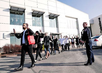 民众高举双手离开商场。 