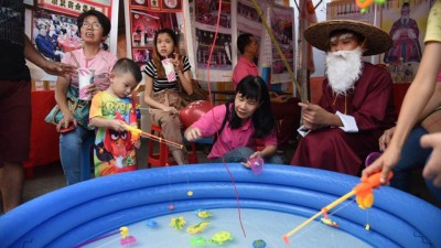 男女老少在知识摊格玩钓鱼游戏。